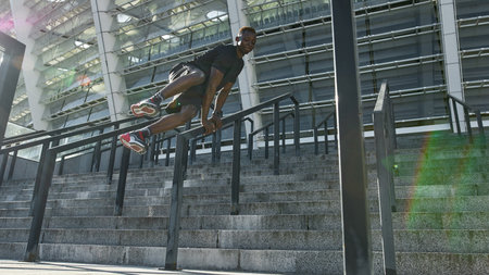 Black sportsman jumping over railing on staircase