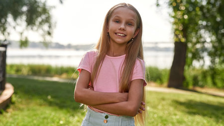 Smiling caucasian girl with crossed arms in park