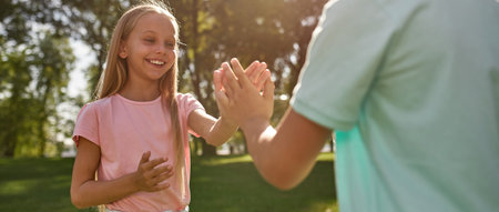 Children playing patty cake game in sunny parkの写真素材