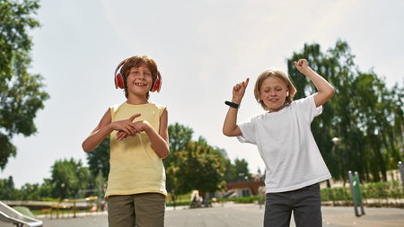 Boy dance near friend listen music in earphones