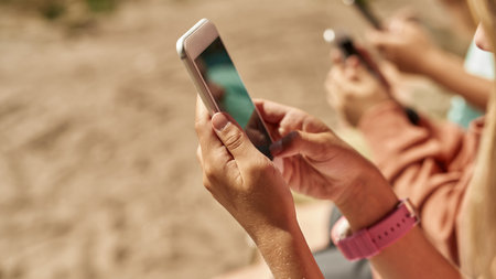 Girl with partial friends use smartphones outdoorsの写真素材