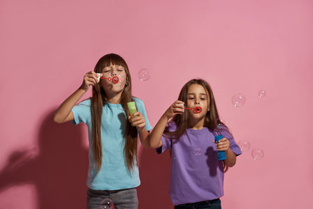 Two caucasian little girlfriends blow soap bubblesの写真素材