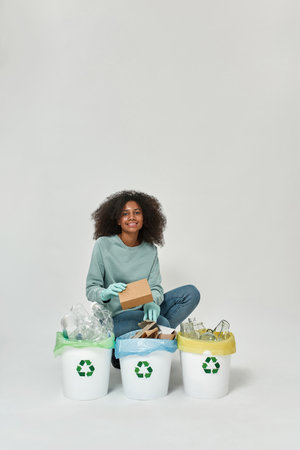 Black girl sort cardboard box in variety dustbinsの写真素材