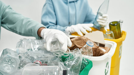 Couple sort garbage in glass, plastic, paper bins