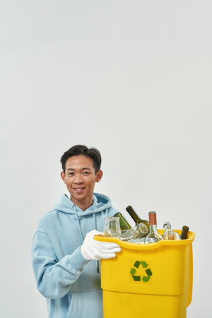 Smiling asian man hold dustbin with glass garbage