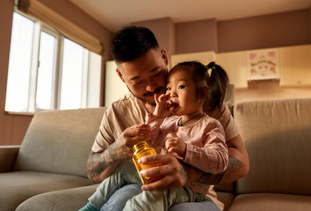 Father look at daughter eat multivitamin jellyの写真素材