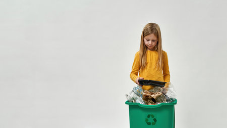 Little girl hold plastic plate from full dustbinの写真素材