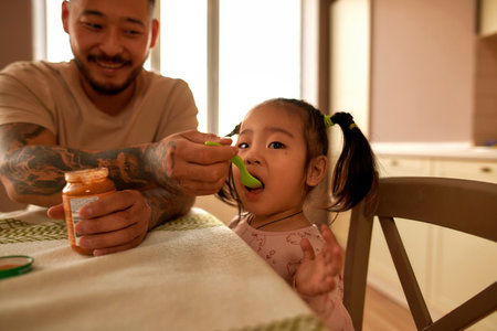 Asian father feeding her little daughter baby foodの写真素材