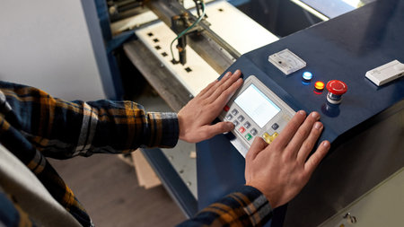 Cropped male worker pressing button on CNC machine