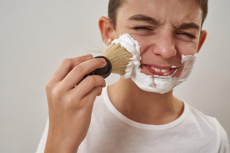Partial of boy smearing shaving foam on face