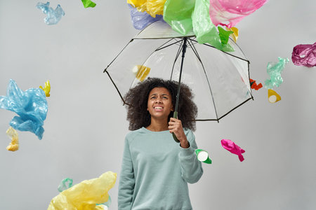 Black girl with umbrella under falling garbage
