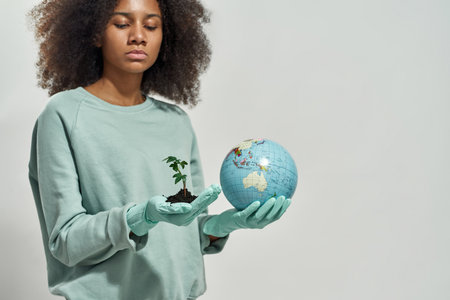 Girl hold and look at globe and plant in handsの写真素材