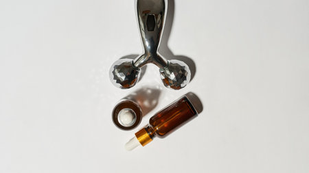 Top view of massager and bottles with oil on white