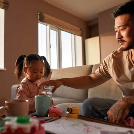 Father on sofa take glass jar from daughter handsの写真素材