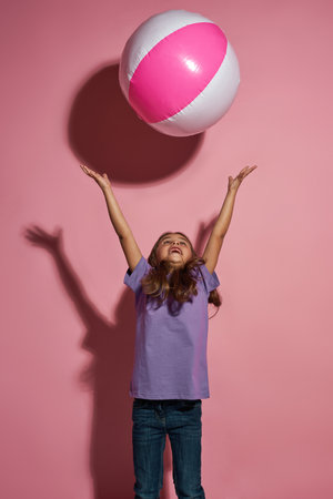 Little girl throwing beach ball and looking upの写真素材