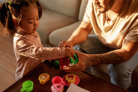 Partial father and daughter play with toy cube