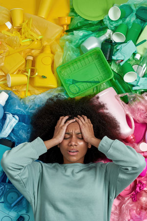 Girl with migraine hold head while lay in garbageの写真素材