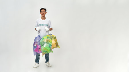 Asian male volunteer holding sorted garbage bags