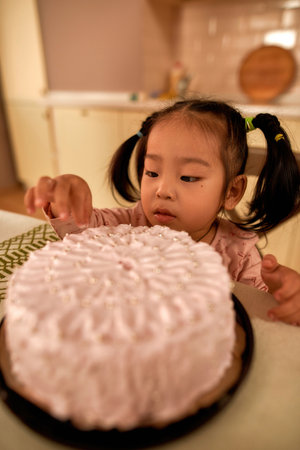 Cute little asian girl eating sweet cake at table