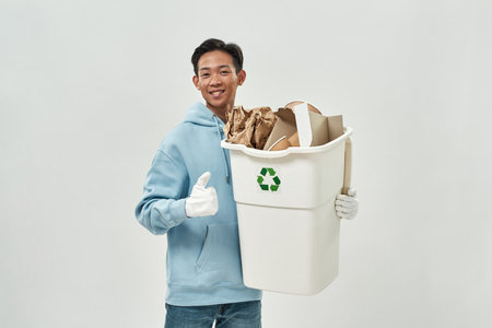 Asian man with thumb up hold bin with cardboardの写真素材
