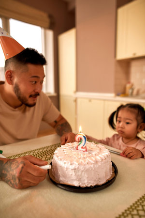 Father look at sad girl look at birthday cakeの写真素材