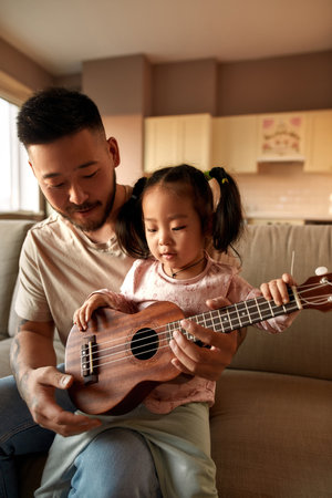 Father teach daughter play notes on ukuleleの写真素材