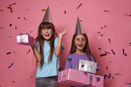 Little girls with gift boxes in flying confettiの写真素材