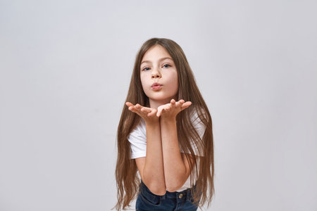 Little girl blowing air kiss and looking at cameraの写真素材