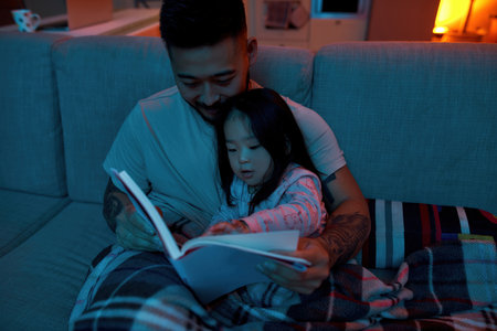 Smiling father reading book with little daughterの写真素材