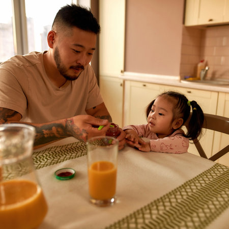 Girl looking at father taking baby food with spoonの写真素材