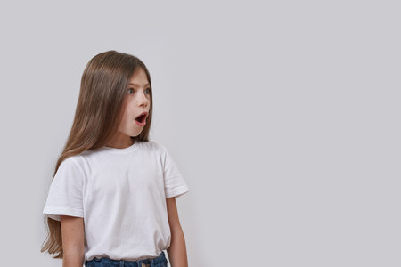 Shocked little girl with open mouth looking awayの写真素材
