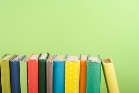 Book stacking. Open hardback books on wooden table and green background. Back to school. Copy space for ad text.の写真素材