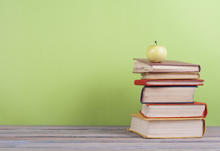Book stacking. Open hardback books on wooden table and green background. Back to school. Copy space for ad textの写真素材