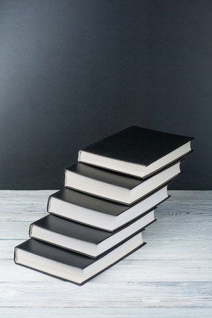 Open books on wooden table, black board background. Back to school. Education business concept.の写真素材