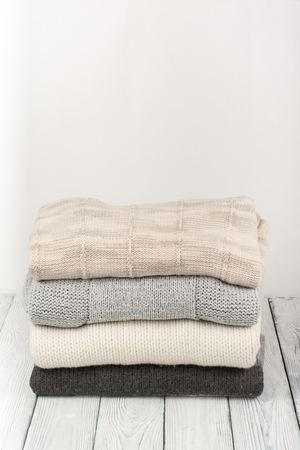Knitted wool sweaters. Pile of knitted winter clothes on wooden background, sweaters, knitwear, space for text.の写真素材