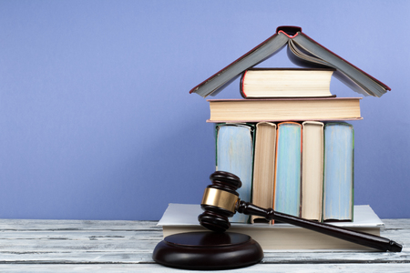 Law concept open book with wooden judges gavel on table in a courtroom or law enforcement office, blue background. Copy space for text.の写真素材