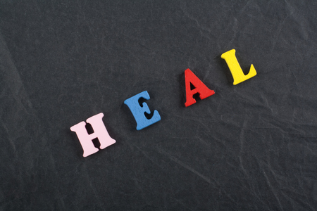 HEAL word on black board background composed from colorful abc alphabet block wooden letters, copy space for ad text. Learning english concept.の写真素材