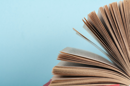 Book stacking. Open book, hardback books on wooden table and blue background. Back to school. Copy...