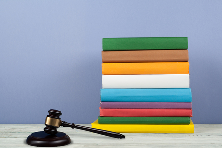 Law concept open book with wooden judges gavel on table in a courtroom or law enforcement office, blue background. Copy space for text.の写真素材