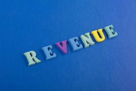 REVENUE word on blue background composed from colorful abc alphabet block wooden letters, copy space for ad text. Learning english concept.の写真素材