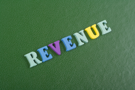 REVENUE word on green background composed from colorful abc alphabet block wooden letters, copy space for ad text. Learning english concept.の写真素材
