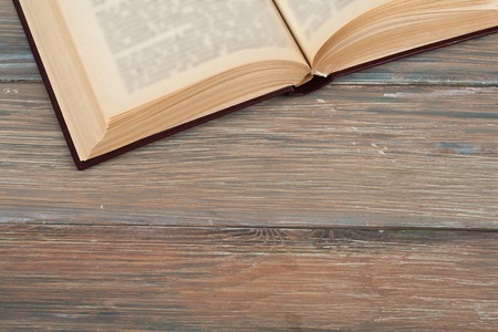 Vintage book, open, on old wooden table.の写真素材