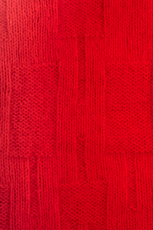 Sweater or scarf fabric texture large knitting. Knitted jersey background with a relief pattern. Braids in knitting . Wool hand- machine, handmade, red.の写真素材