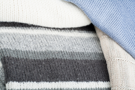 Knitted wool sweaters. Pile of knitted winter clothes on wooden background, sweaters, knitwear, space for text.の写真素材