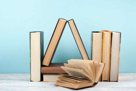 Open book, hardback colorful books on wooden table, blue background. Back to school. Copy space for text. Education business concept.の写真素材