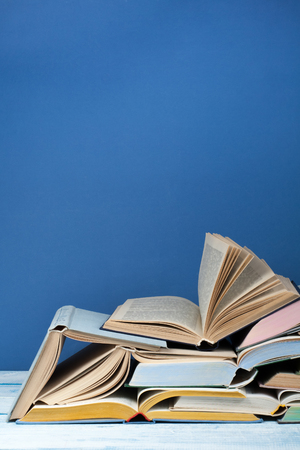Open book, hardback colorful books on wooden table, blue background. Back to school. Copy space for text. Education business concept.の写真素材