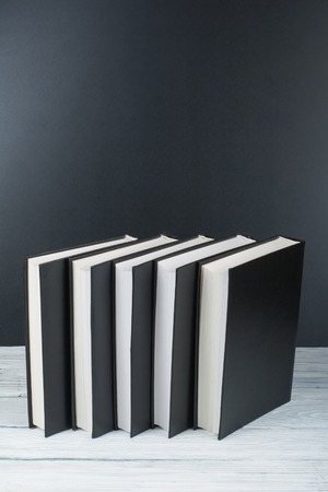 Open books on wooden table, black board background. Back to school. Education business concept.