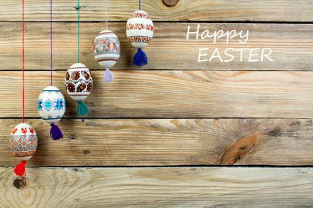 Happy Easter card. Colorful shiny easter eggs on wooden table background. Copy space for text.の写真素材