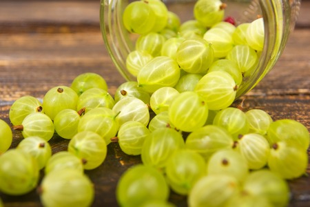 gooseberries on wooden table background, spilled from a spice jar