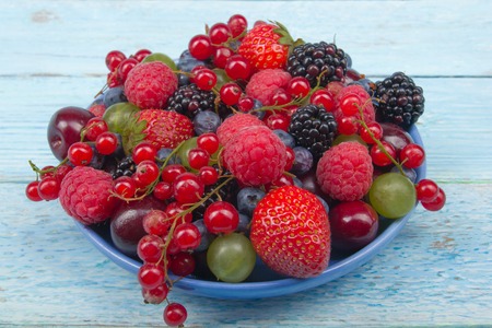 Various summer Fresh berries in a bowl on rustic wooden table. Antioxidants, detox diet, organic...